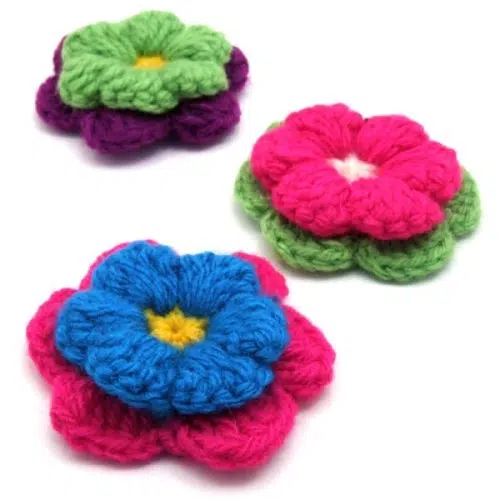 A picture of some crocheted flowers that have been put on a pin.