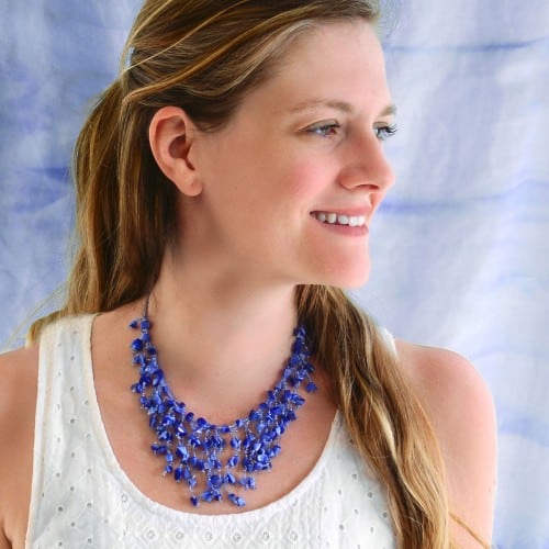 A picture of a young lady wearing a purple abundant stone necklace.