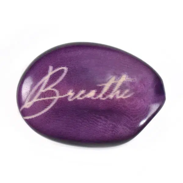 A tagua seed that says breathe on it