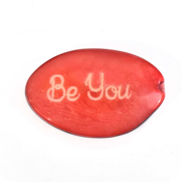 A tagua seed that says be you on it