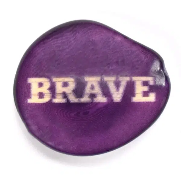 A tagua seed that says brave on it