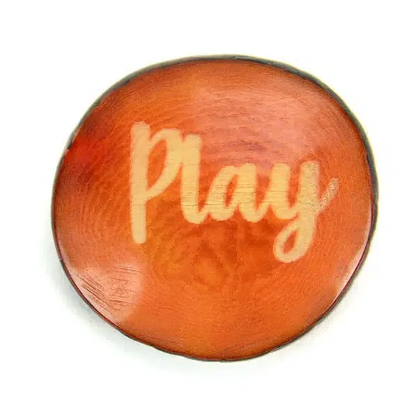 A tagua seed that says play on it