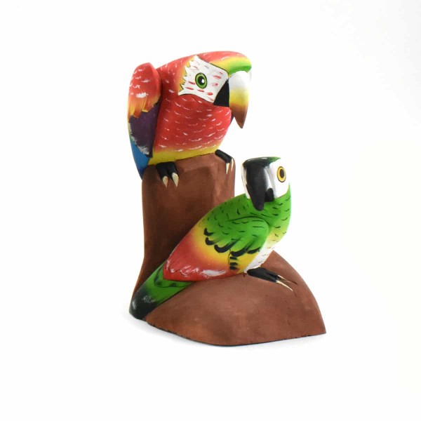A bright red parrot looking at a bright green with red parrot, these are made out of balsa