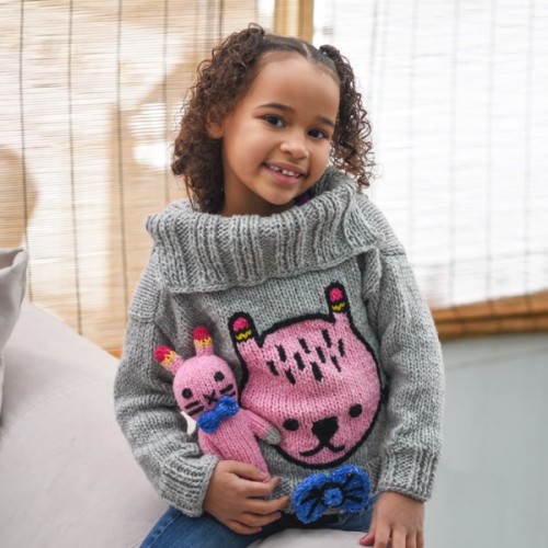 young child wearing the dandy bunny sweater, while holding the dandy pal bunny