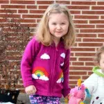 A young child wearing over the rainbow sweater, available in sizes 2, 4, and 6.