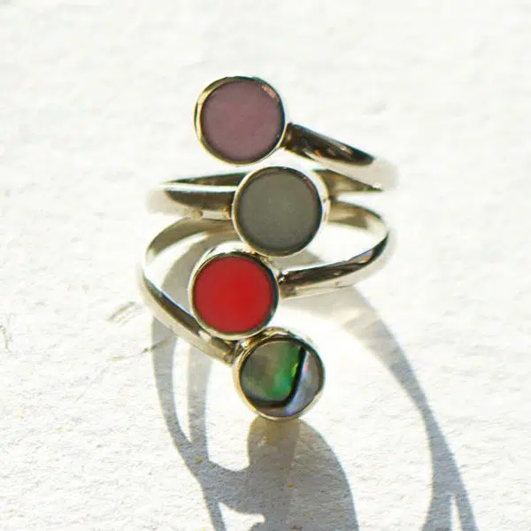 A close up picture of four different semi precious stones in the quartet ring, the color of these stones are purple, grey, red, and green.
