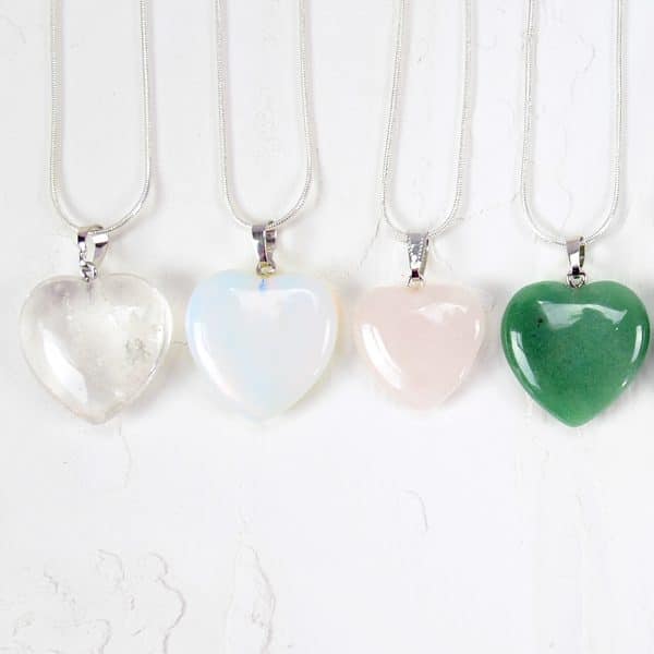A picture of four different heart necklaces, the color of these are, clear, white/blue, light pink, and light green.