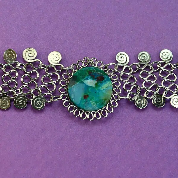 A picture of a alpaca mesh necklace, with a semi precious stone in the middle, the color of the stone is turquoise.