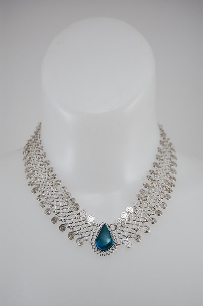 A picture of the alpaca mesh necklace with a semi precious stone in the middle, the color of that stone is turquoise.
