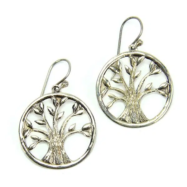 A silver earring that has a tree in the middle of it.
