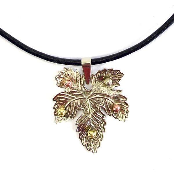 A picture of a silver maple leafs hanging on a necklace.