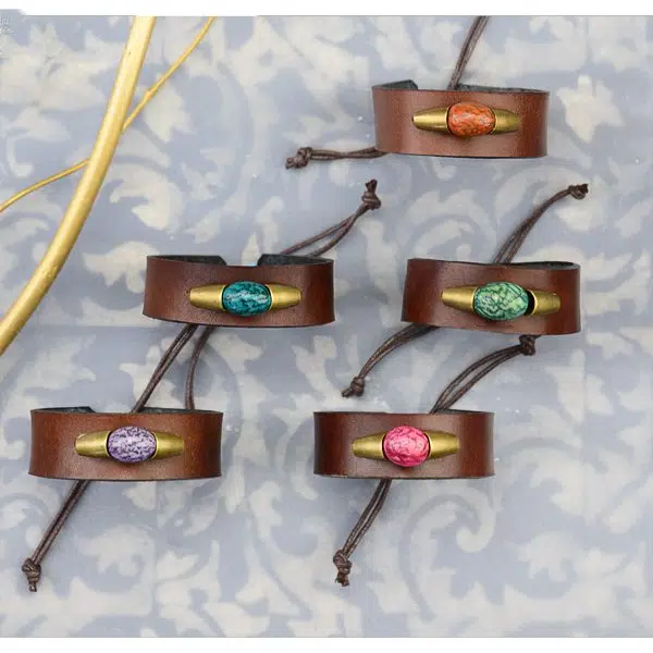 A picture of a leather bracelet with a dyed pambil seed.