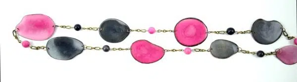 The fettered set, made with tagua slices on a bronze toned chain. the color of this necklace is pink and black.