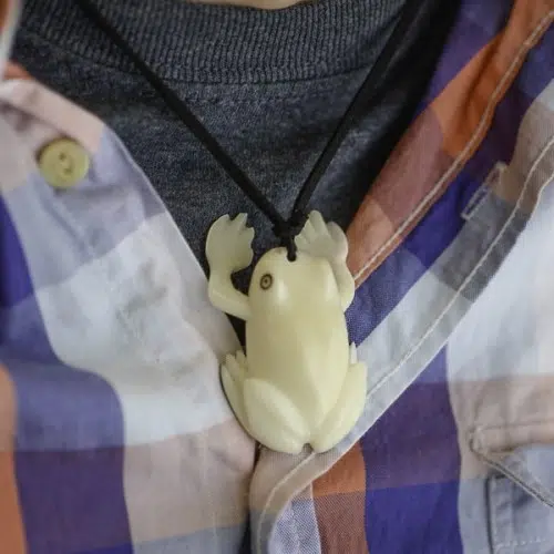 A picture of a carved frog necklace made from tagua.