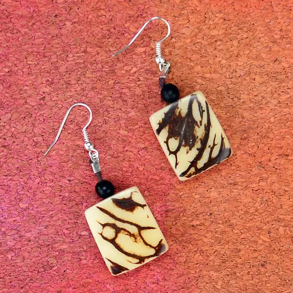Two earrings that have been made from tagua seeds, that has a neutral look.