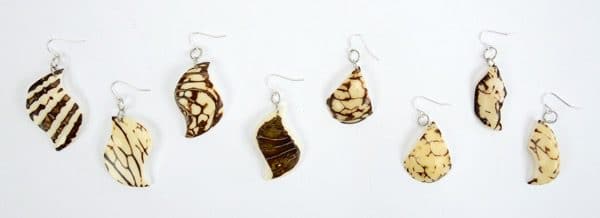 A picture of earrings that has been made from tagua nuts, and have a verity of design on them.