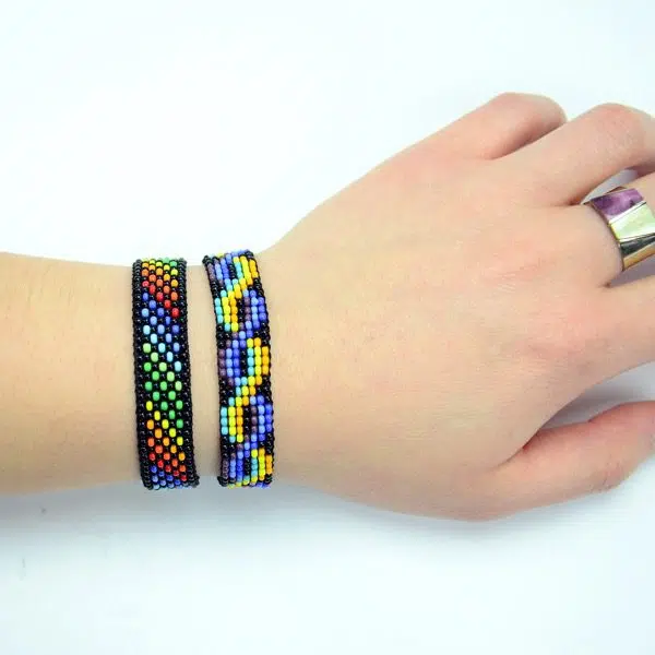 A picture of an arm wearing the woven bead bracelet, the colors are the bracelet are rainbow, and blue and yellow.