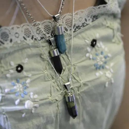 A close up picture of the pendulum necklace, this necklace comes in a few colors, turquoise, black, and green.