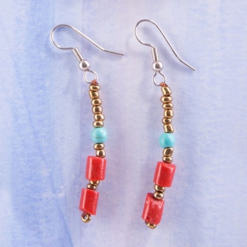 A close up picture of the eminence earrings, red coral with turquoise beads come with brass accents.