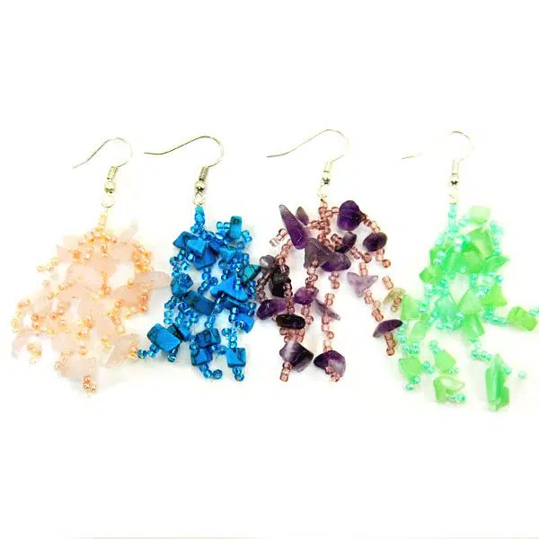 A close up picture of the abundant stone earrings, the colors in this picture are, pink, turquoise, purple, and green.