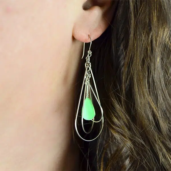 A close up of someone wearing the suspended form earrings.