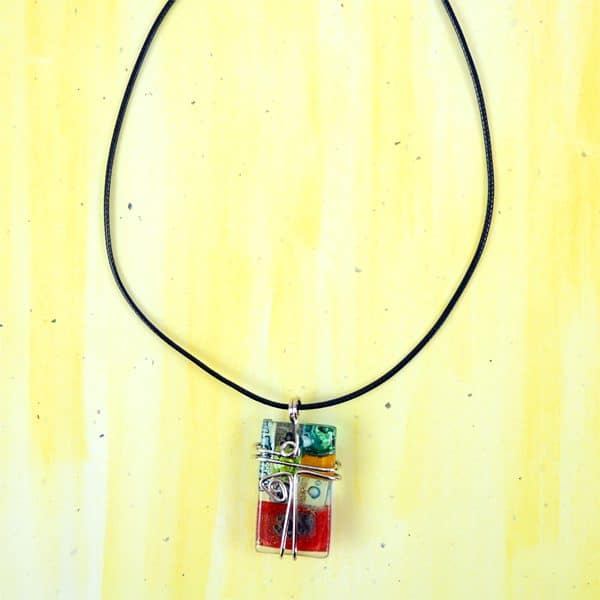 A picture of the art glass necklace, different colors are fused together with in the glass.