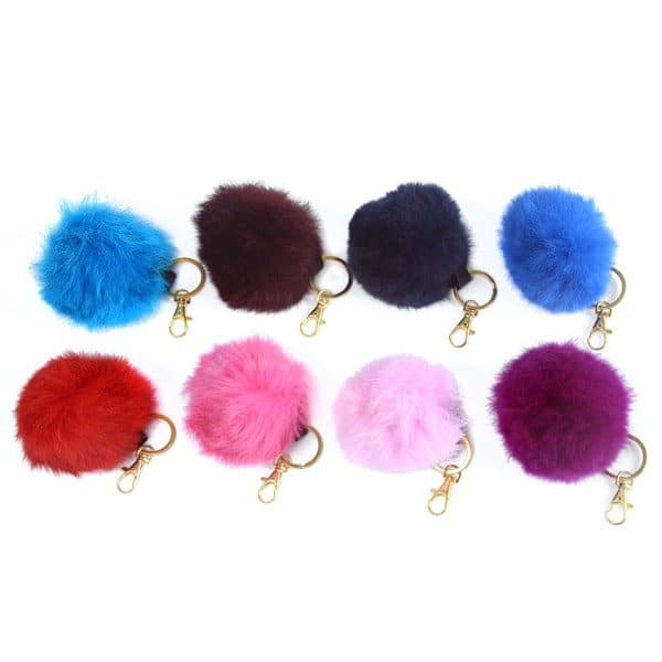 showing colors for the rabbit fur pom pom spaced out, the colors are, light blue, violet, dark blue, blue, red, pink, light pink, magenta