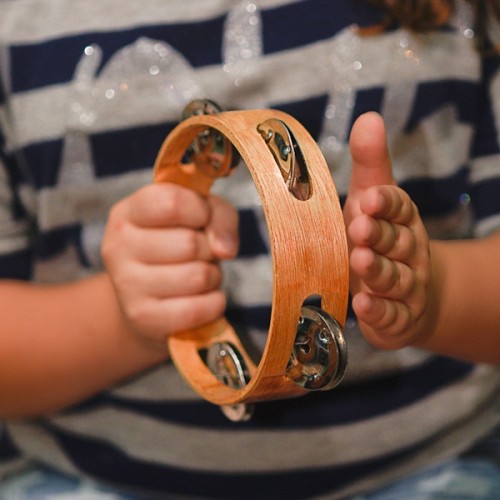 A young kid playing with the tambourine
