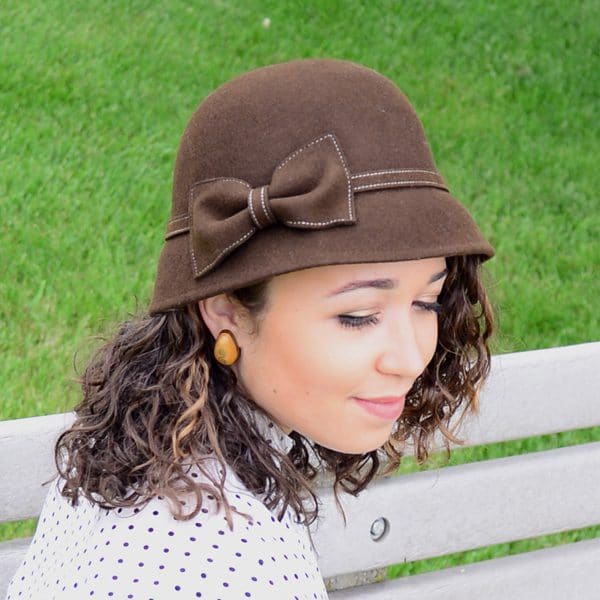 A young women wearing a tall brown bell hat with a bow
