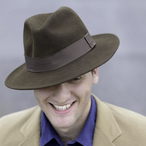 A young man wearing the wool fedora, the color of the fedora is grey