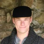 A young man wearing a wool flat cap in the color black