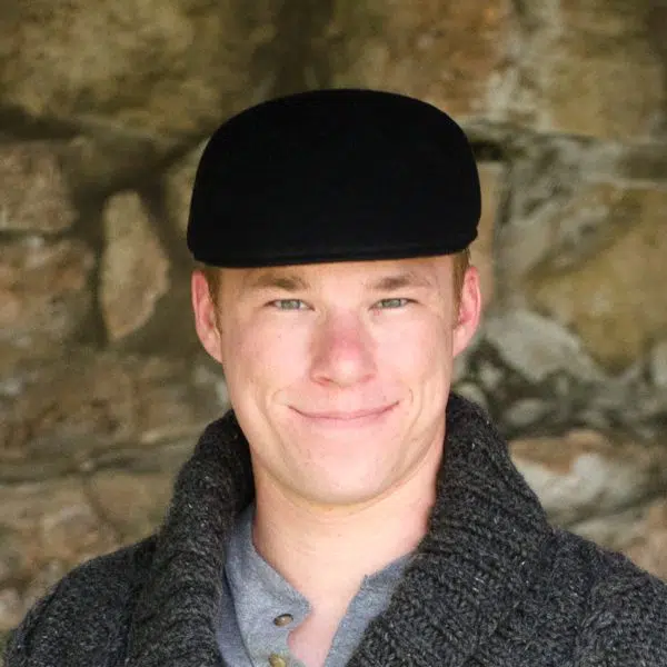 A young man wearing a wool flat cap in the color black