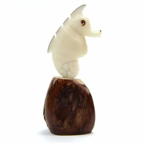 A sea horse sitting on top of a tagua seed, hand carved and made from tagua seeds.