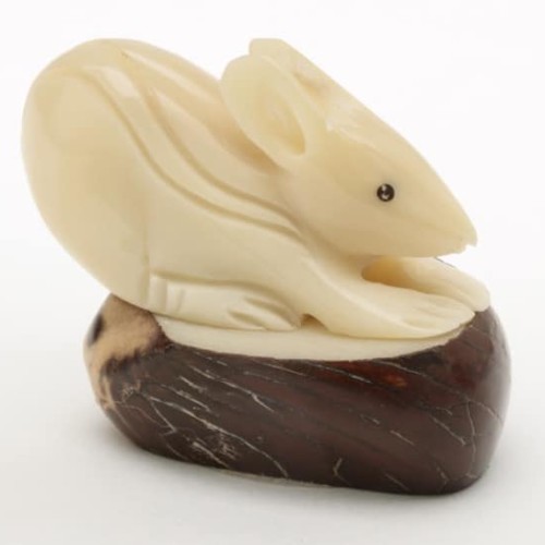 A hand carved mouse sitting on top of a tagua nut