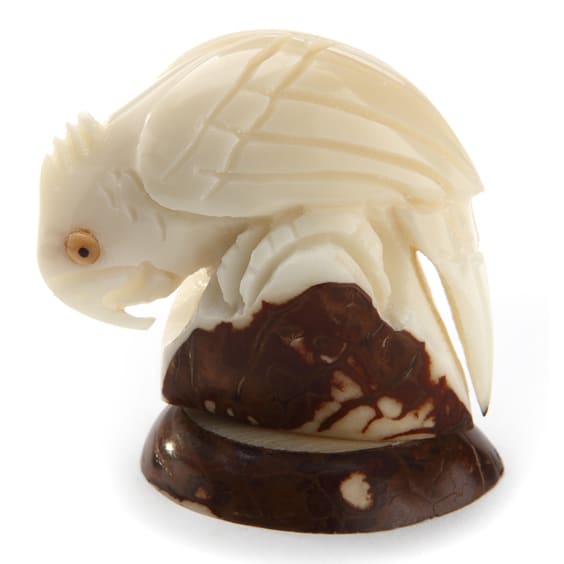 A detailed carving of a cockatoo on a rock, all of these carvings are made from tagua seeds