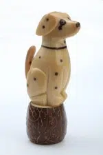 a tagua carving of a dalmatian sitting on a wood log. these carvings are made out of a tagua seed