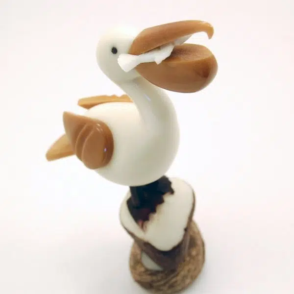 A palican sitting on a rock, hand carved and made from tagua nuts.