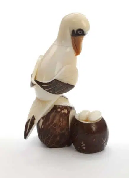 A sea bird with its nest sitting on some rocks, made and hand carved from tagua seeds