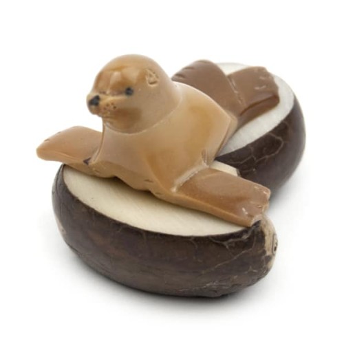 A sea lion laying on a rock, hand carved from tagua seeds