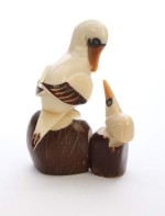 A sea bird with a baby sea bird sitting on rocks, made and hand carved out of tagua seeds