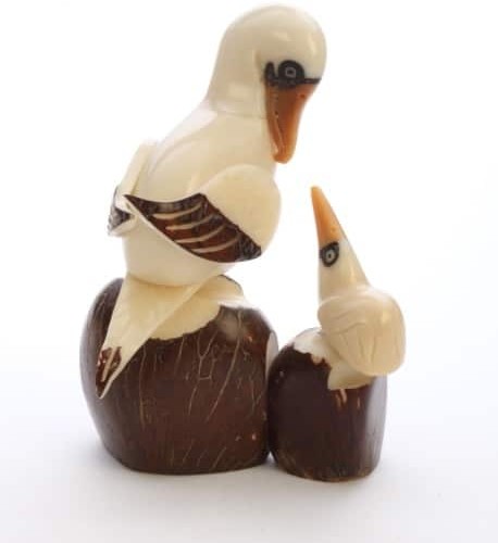 A sea bird with a baby sea bird sitting on rocks, made and hand carved out of tagua seeds