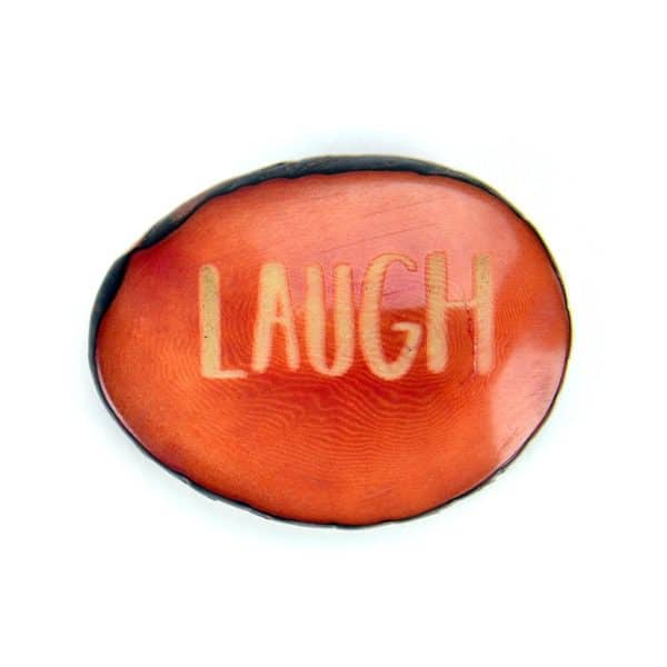 A tagua seed that says laugh on it