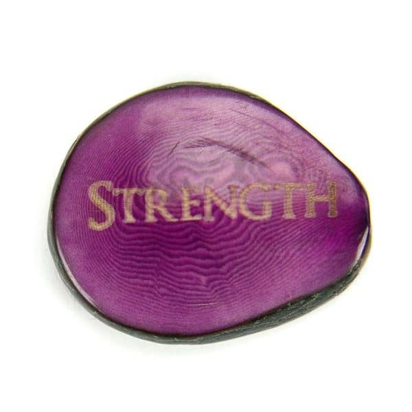 A tagua seed that says strength on it