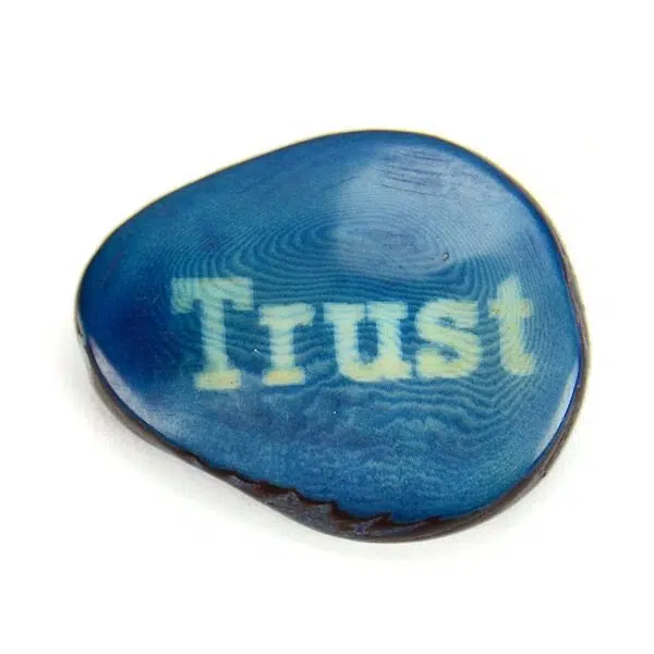 A tagua seed that says trust on it