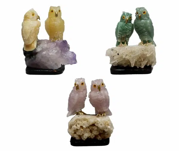 A picture of three different semi precious stone owl pairs, they come in the color of, yellow with a purple rock, green with a white rock, and pink with a white rock.