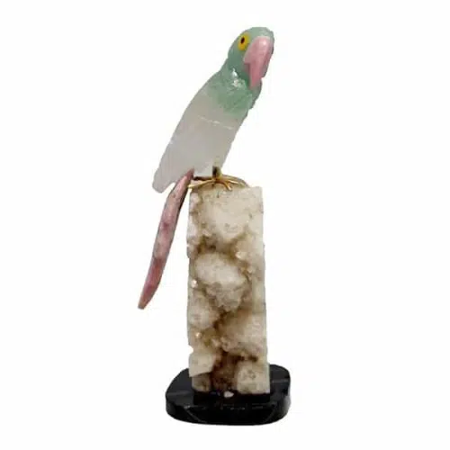 a parrot sitting on a semi precious stone parrot, the colors of the stones are, white with brown.