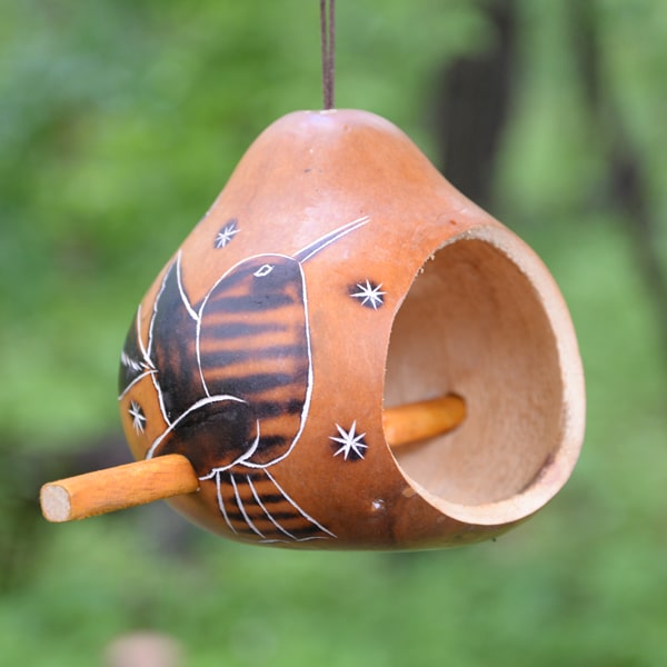 A bird house with designs torched into the side.