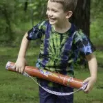 A young kid playing with a large rain stick