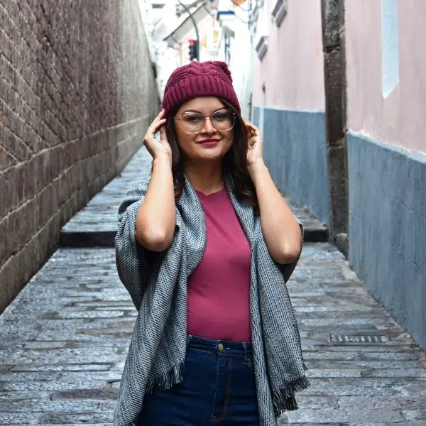 A young women wearing a knit hat that has patterns on it with a pompom on top of the hat