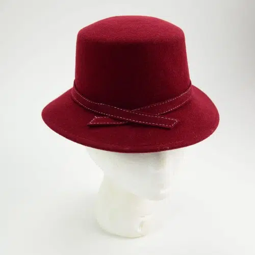A maroon hat made from felt with a mix of a bowler and fedora style